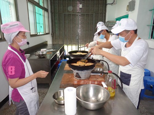The instructor teaches the inmates cooking methods and techniques.